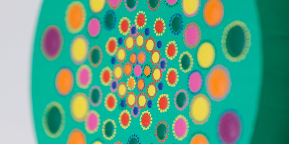 Colourful dot mandala on round canvas, yellow green blue pink orange purple on green background