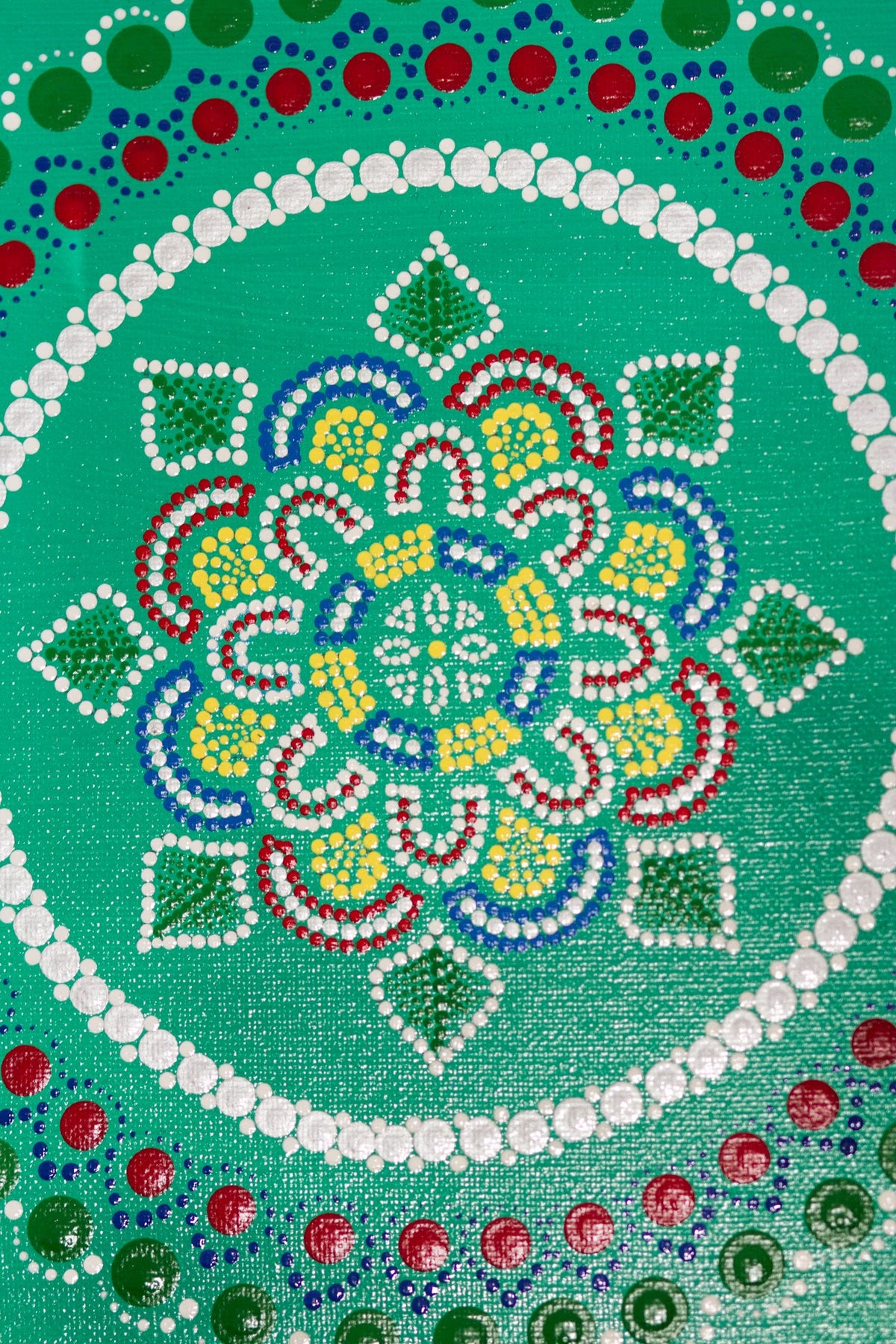 Dot mandala detail, red green yellow blue on green background