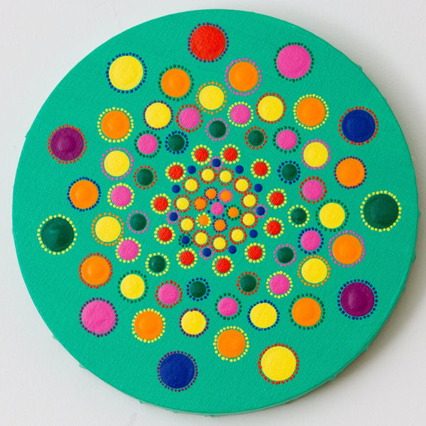 Colourful dot mandalaa on round canvas, red yellow pink green blue purple on green background 