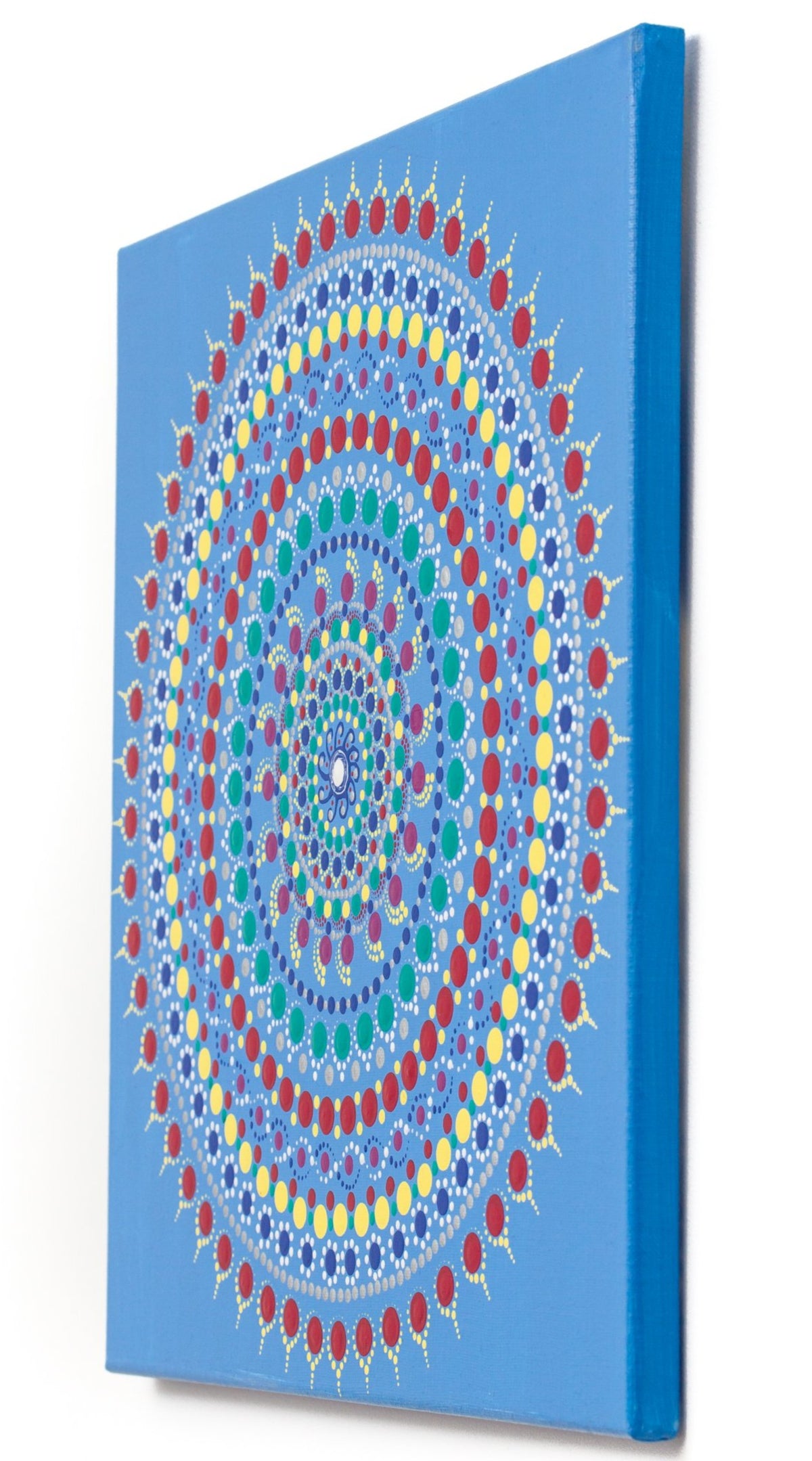 Colourful dot mandala canvas,  red yellow green purple white, on blue background