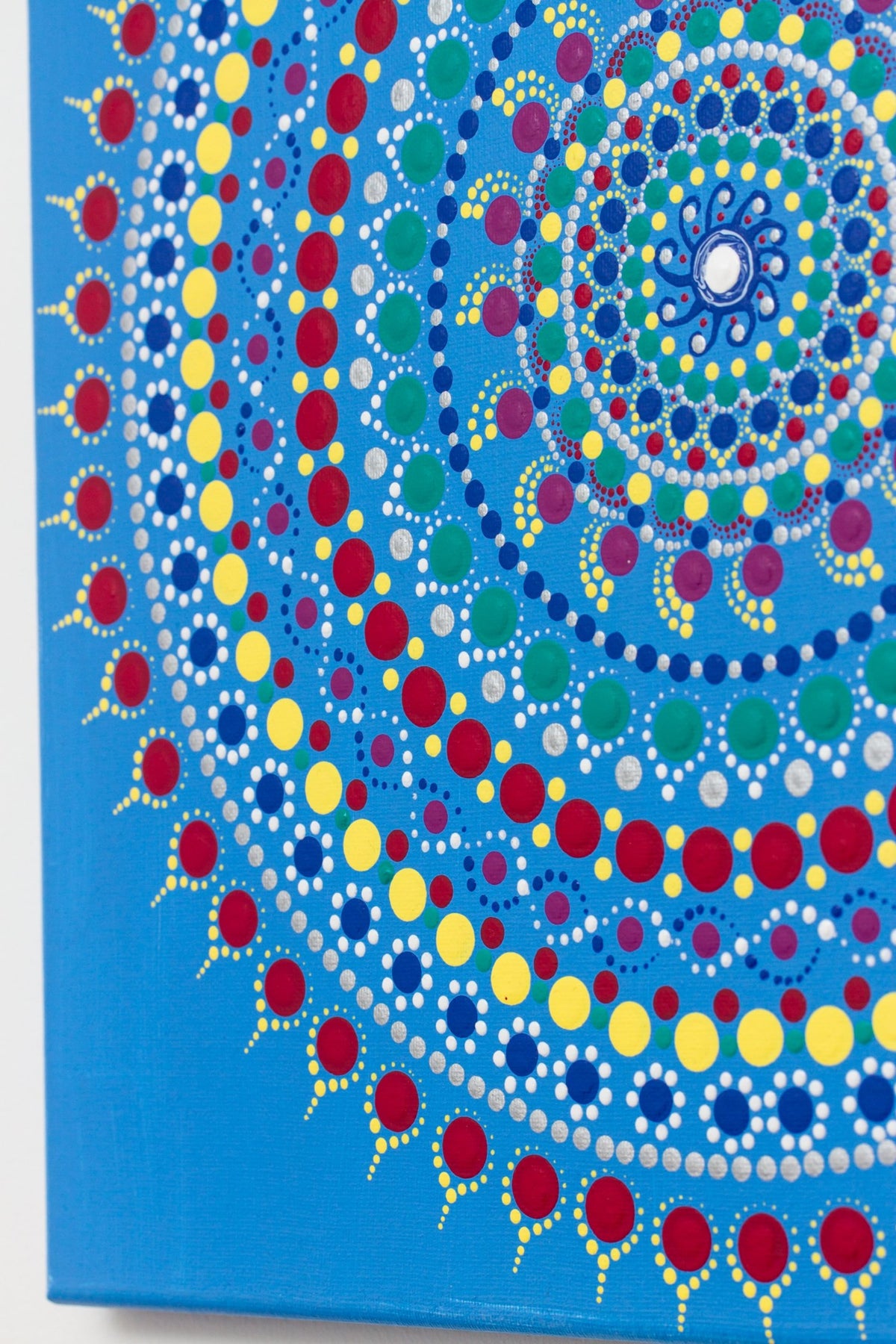Colourful dot mandala detail, blue background, red yellow green purple white