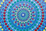 Colourful dot mandala detail, red yellow green purple white on blue background